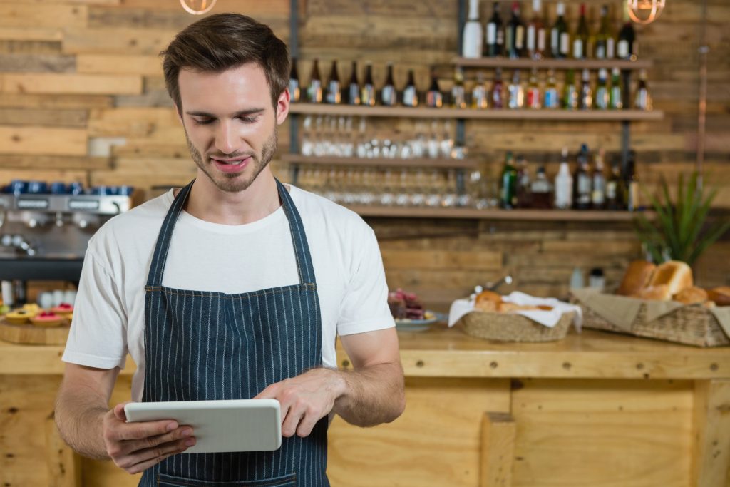 man in apron looking at tablet