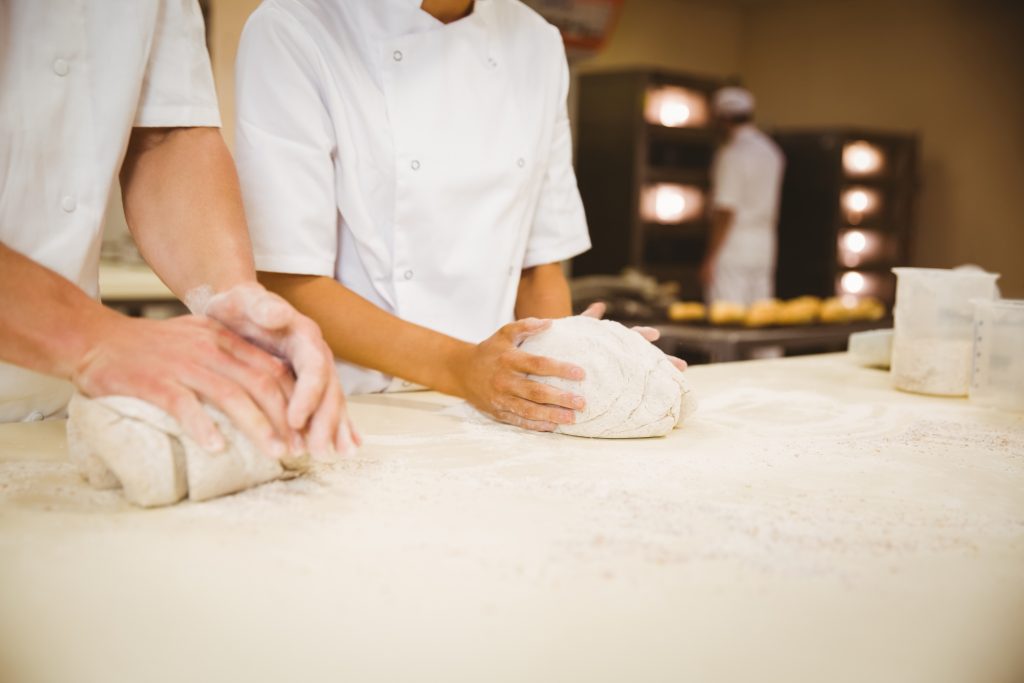 two people kneading bread